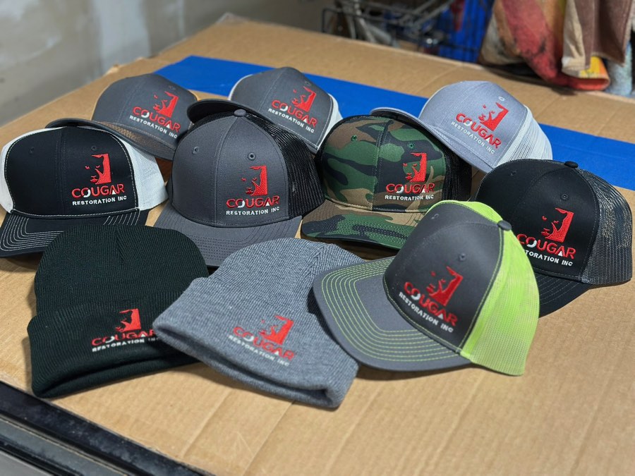 Assorted trucker hats and beanies with a red and white Cougar logo