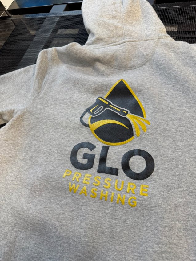 Gray hoodie printed with the black and gold GLO Pressure Washing logo