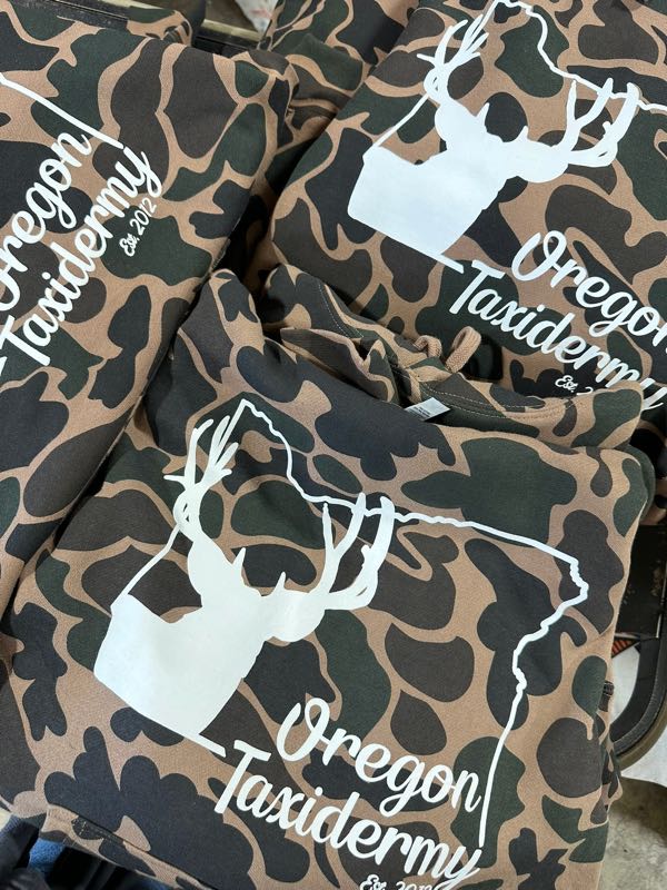 Brown camo hoodies printed in white with the Oregon Taxidermy deer and state logo
