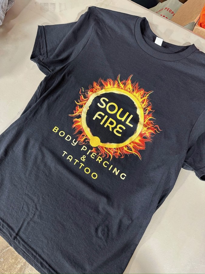 Black t-shirt with a full-color flaming Soul Fire Body Piercing and Tattoo logo